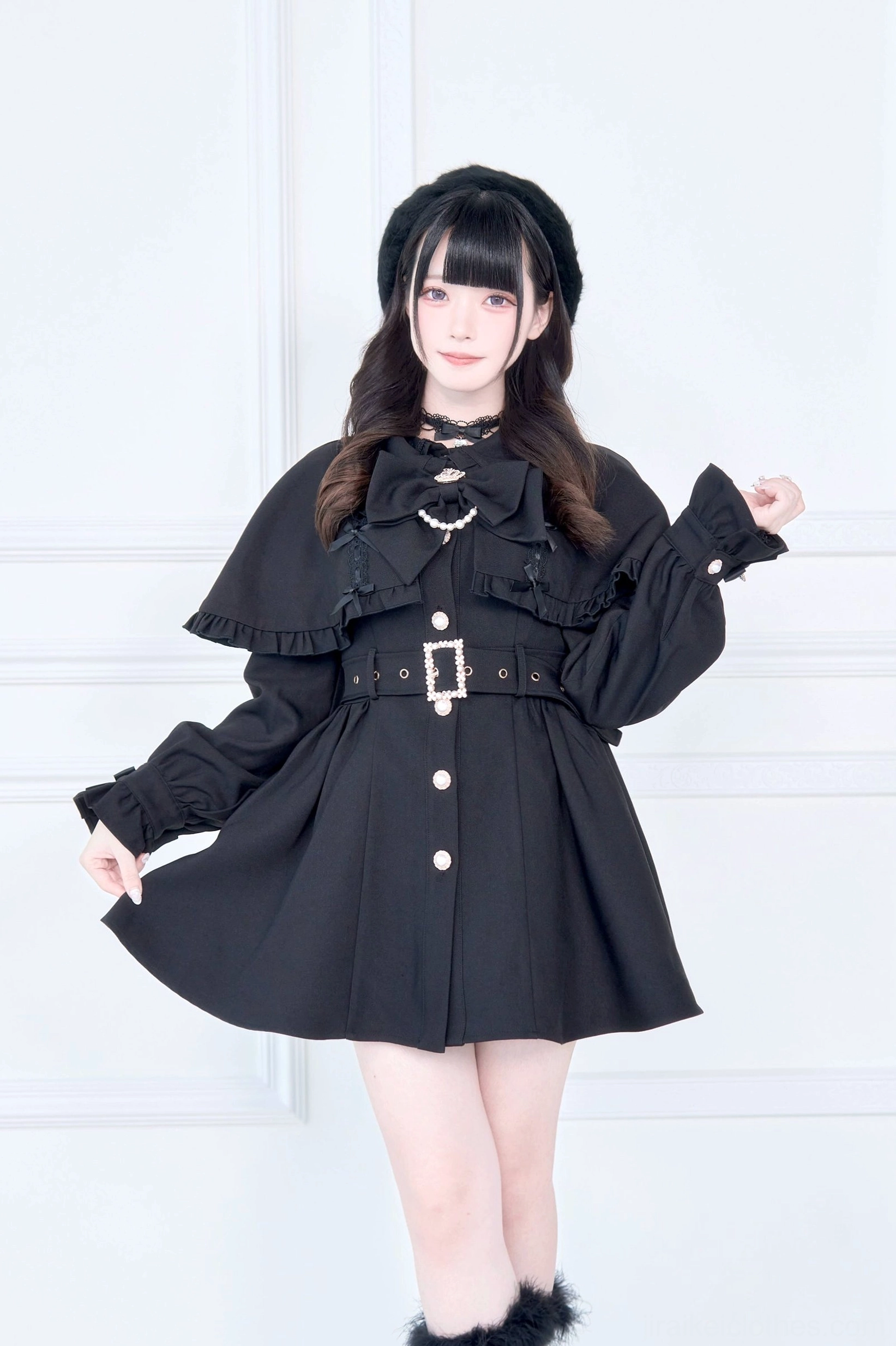 Solid black Jirai Kei cape collar trench coat with metal waist buckle and front button closure front three-quarter standing view