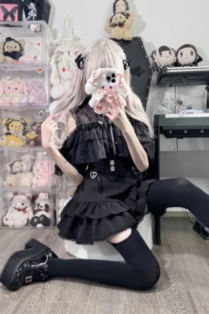 Solid black multi-layer ruffled Jirai Kei skirt paired with black fitted blouse and platform leather shoes, full-body front mirror selfie with waist belt detail