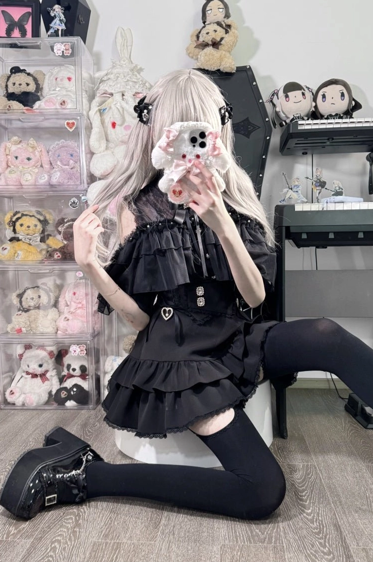 Solid black multi-layer ruffled Jirai Kei skirt paired with black fitted blouse and platform leather shoes, full-body front mirror selfie with waist belt detail