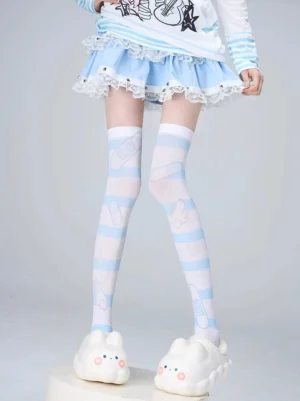 Over-the-knee velvet socks with light blue striped and bandage bear prints, worn with blue frilled lolita skirt and cute bunny slippers, frontal full leg view showcasing tenshi angel jirai kei aesthetic