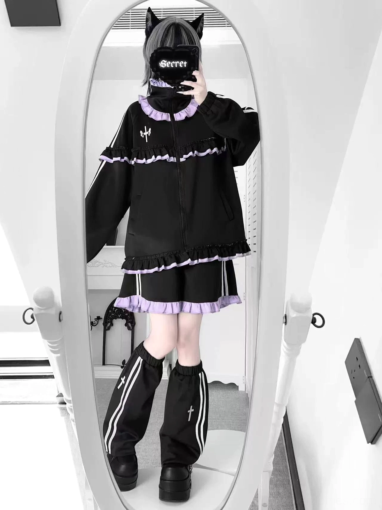 Black-purple ruffle Tenshi Kaiwai Jirai Kei set with frill trim collar, short skirt and striped leg warmers styled in mirror selfie with cat-ear mask