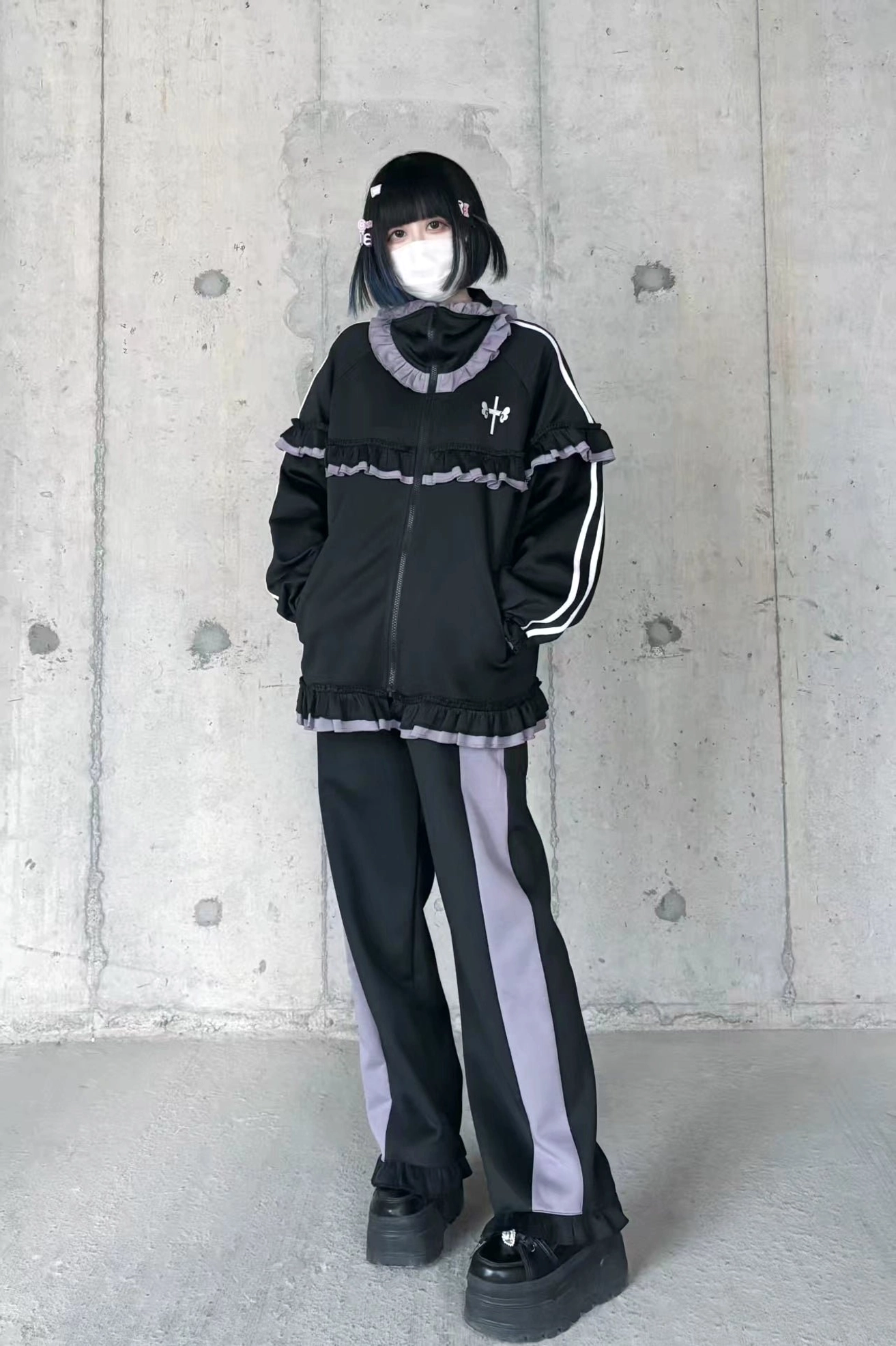 Black-purple ruffle Tenshi Kaiwai tracksuit with side stripe wide-leg pants, zip-up jacket and ruffled collar flat lay outdoor concrete