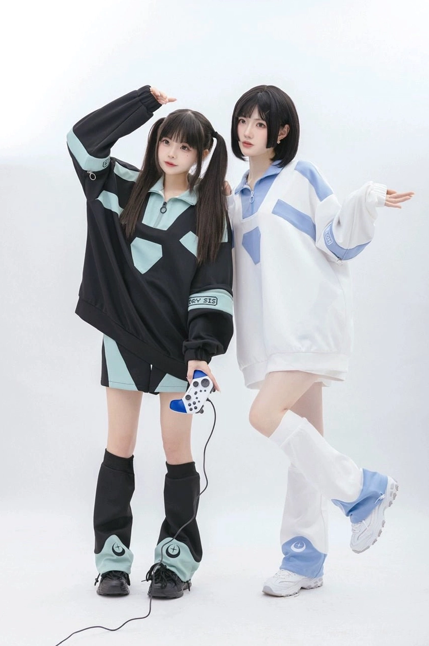 Side standing view of Tenshi Kaiwai black sweatshirt and shorts set with sleeve text prints and removable design, one model holding game controller
