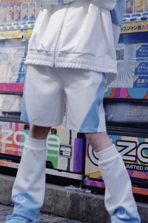 Tenshi Kaiwai light blue and white color-block sports shorts front view worn with streetwear aesthetic against Japanese vending machine backdrop