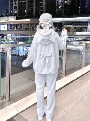 Back view of light blue cat ear hoodie set with lace-trimmed hood and matching wide leg sweatpants, back bow decor detail visible, night outdoor shopping mall setting