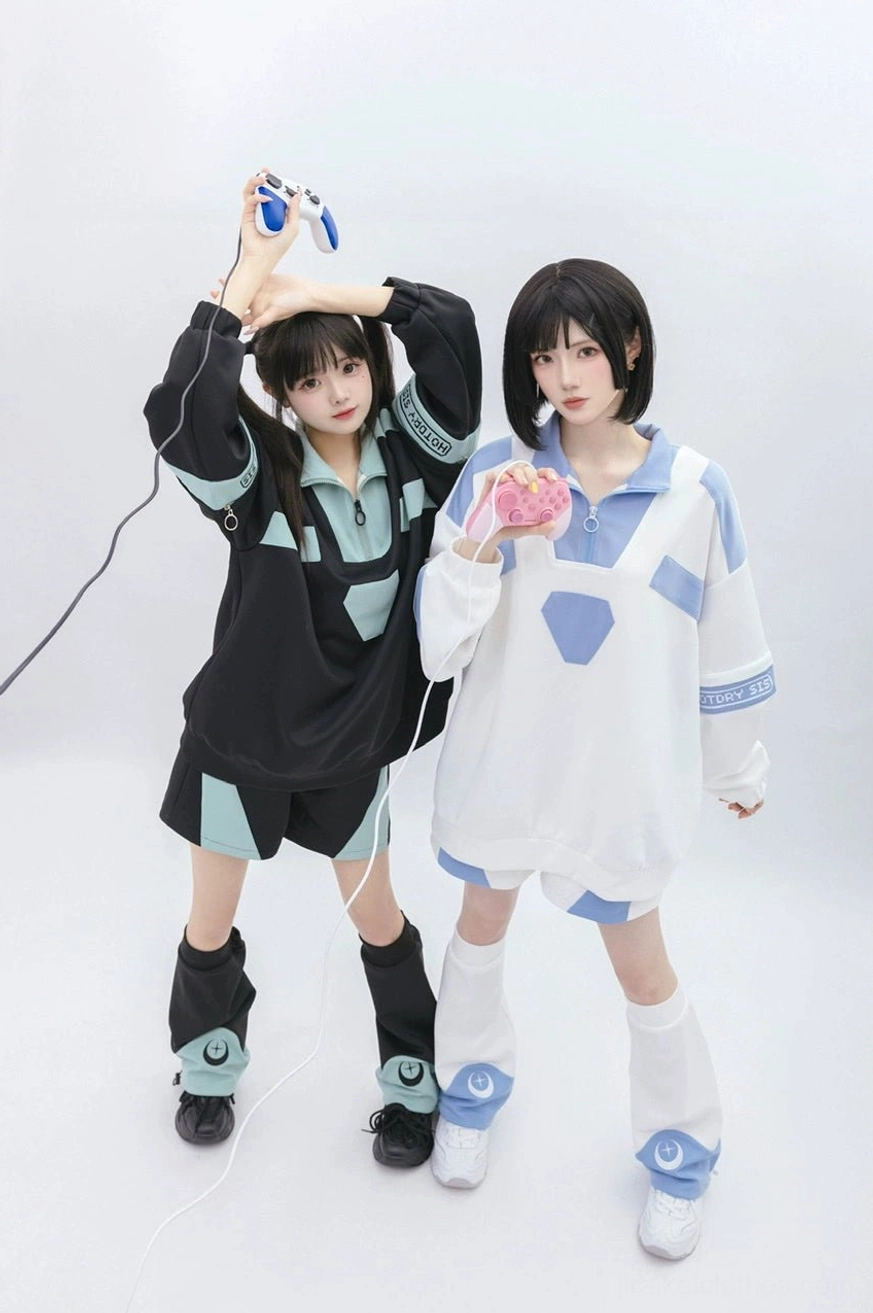 Two female models wearing complete Tenshi Kaiwai gaming loungewear set with matching leg warmers featuring crescent star prints, both holding gaming peripherals