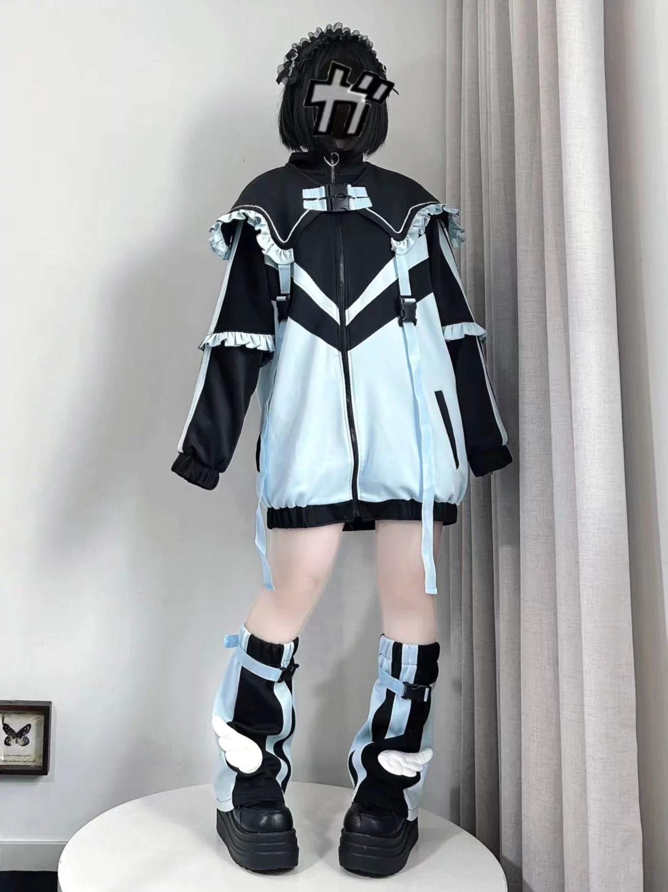 Tenshi Kaiwai color block jacket with ruffled sleeve trims and buckle collar detail, back full-body view with cross mark head accessory and patterned leg wear