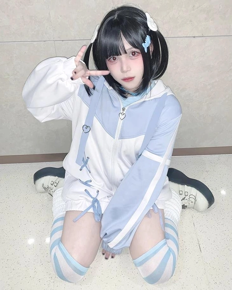 Blue-white Tenshi Kaiwai lace-up hooded sport jacket with contrasting color blocks, cross-lacing detail, and matching leg warmers on model wearing twin-tails