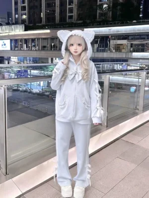 Light blue tenshi kaiwai cat ear zip-up hoodie with removable bow and lace sleeves paired with matching wide leg sweatpants, front full-body view on lolita-style model in night outdoor shopping mall