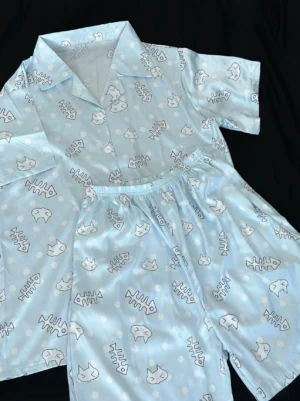 Tenshi Kaiwai light blue cat print short-sleeve pajama set with matching pants, flat lay perspective on black background displaying full outfit styling