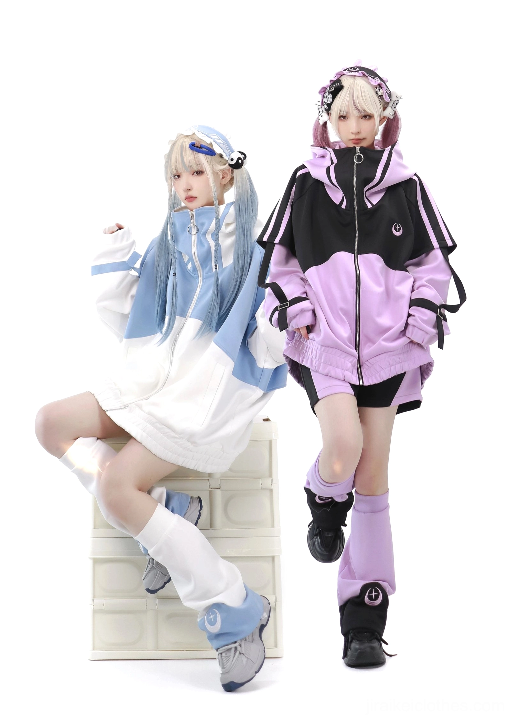 Low-angle seated shot of Tenshi Kaiwai color-block sports sets featuring two models leaning on white block prop wearing oversized jackets worn as mini dress with leg warmers