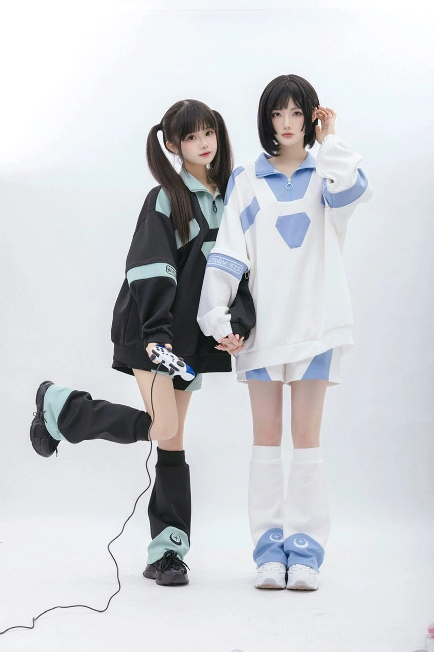 Dynamic standing view of matching Tenshi Kaiwai two-piece sporty set with one model lifting leg, featuring game controller prop and coordinating leg warmers