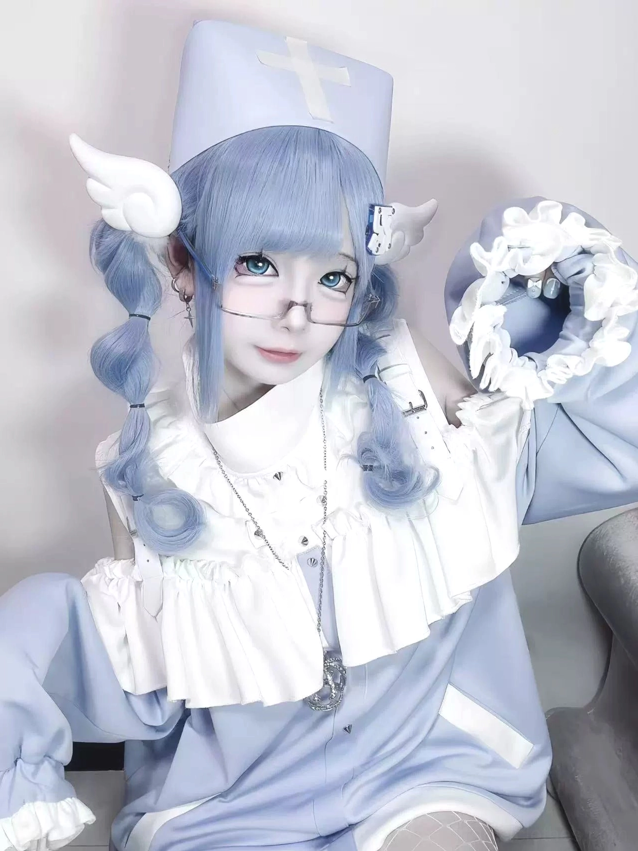 Pastel blue Tenshi Kaiwai off-shoulder sweatshirt close-up with ruffled collar and wing hair clips worn by model with twin blue braids