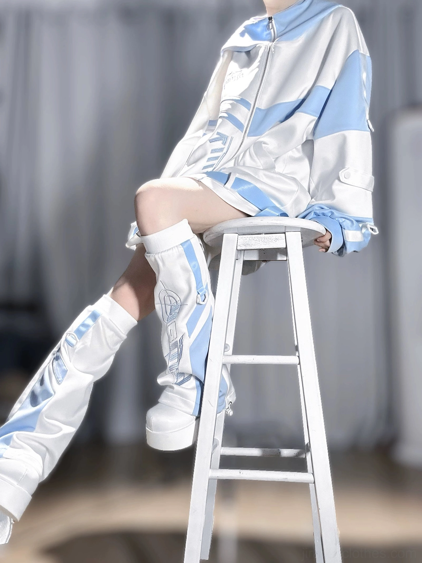 Tenshi kaiwai techwear complete outfit side sitting view on step stool, printed leg warmers coordination, relaxed loose fit, and blue color block details