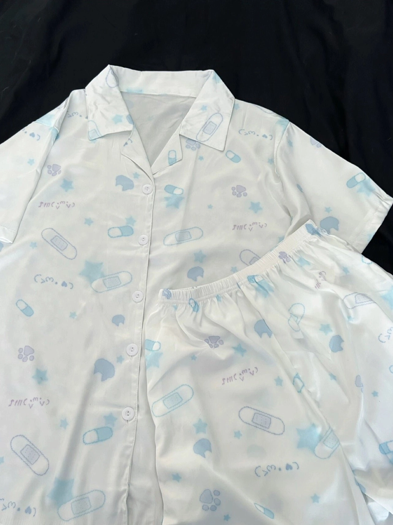 White Tenshi Kaiwai cat print pajama set with short sleeves and shorts, premium cotton fabric texture detail, flat lay product photography on neutral background