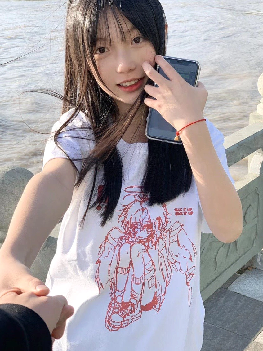 Female model wearing white Tenshi Kaiwai crying angel graphic t-shirt riverside outdoor setting front view Jirai Kei style