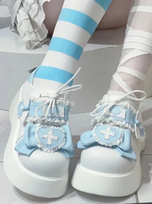 Water blue and white Jirai Kei platform shoes with cross badge and decorative bow, shown in low front angle with striped blue-white legwear and thick white platform sole