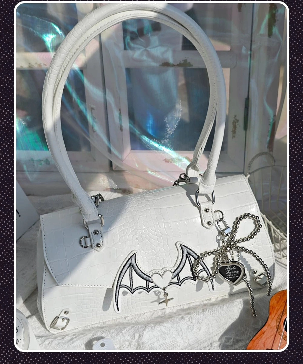 White bat-style croc Jirai Kei handbag with bat-wing and bow metal charms dual carrying straps glass window setting flat lay