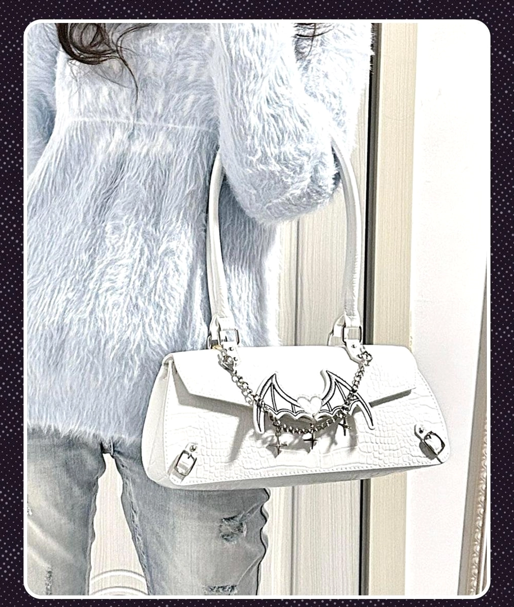 White croc texture bat-themed shoulder bag carried on back of model in fuzzy coat and ripped jeans with silver bat-wing chain decor