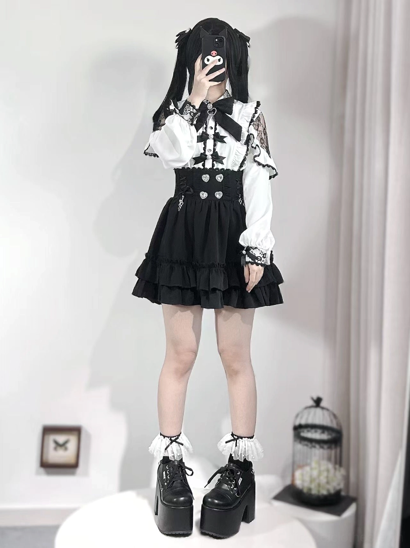 White and black Jirai Kei full-body coordinate featuring heart waist button blouse, layered ruffled black skirt, platform heels, and frilly socks ensemble