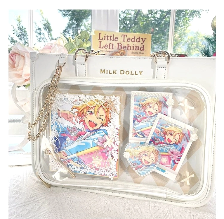 White checkered ita bag flat lay showing clear display window and anime print decorations with garden window background