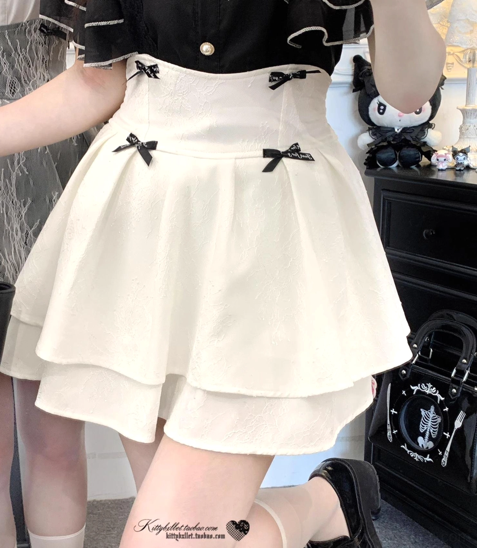 Back side close-up view of white double-layered jirai kei lolita skirt on female model, displaying high waist design, multiple small black bows, and clean layered ruffle hem