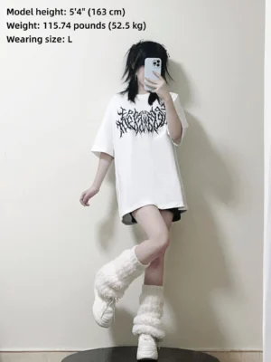 White oversized gothic print cotton t-shirt jirai kei aesthetic worn by female model size L with fuzzy leg warmers and platform shoes front view