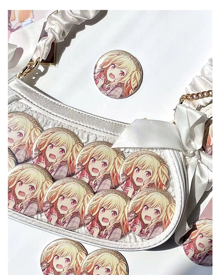 White ita bag interior display overhead close-up showing multiple anime badges, satin bow decorations, clear window functionality, and badge arrangement possibilities