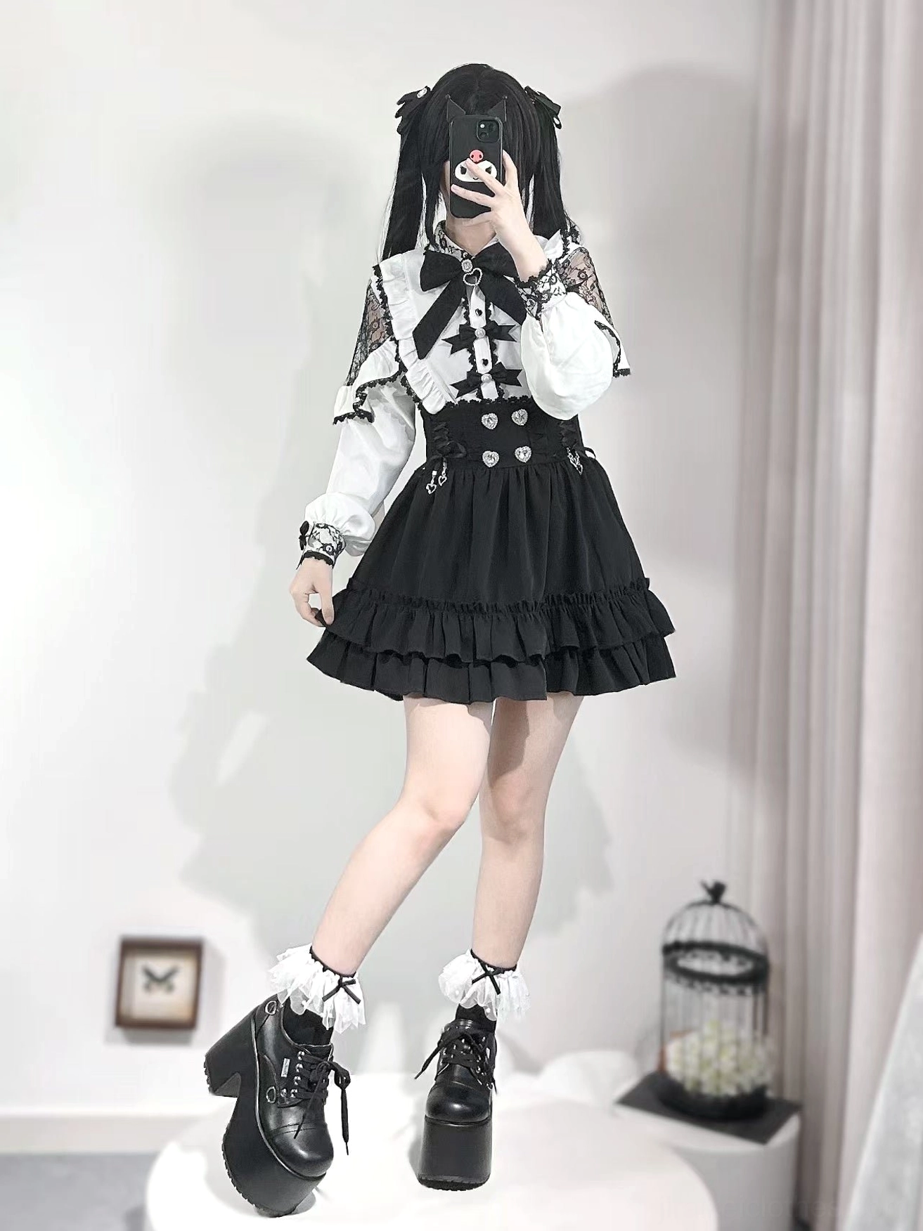 White Jirai Kei lace blouse detail shot emphasizing heart-shaped button closure, black bow embellishments, ruffled design, and delicate lace construction
