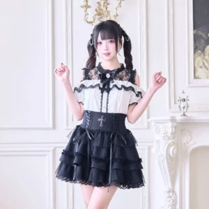 White off-shoulder Jirai Kei blouse featuring black lace cutout upper, sparkling rhinestone bow tie accent, and decorative ruffles displayed on model with cross charm