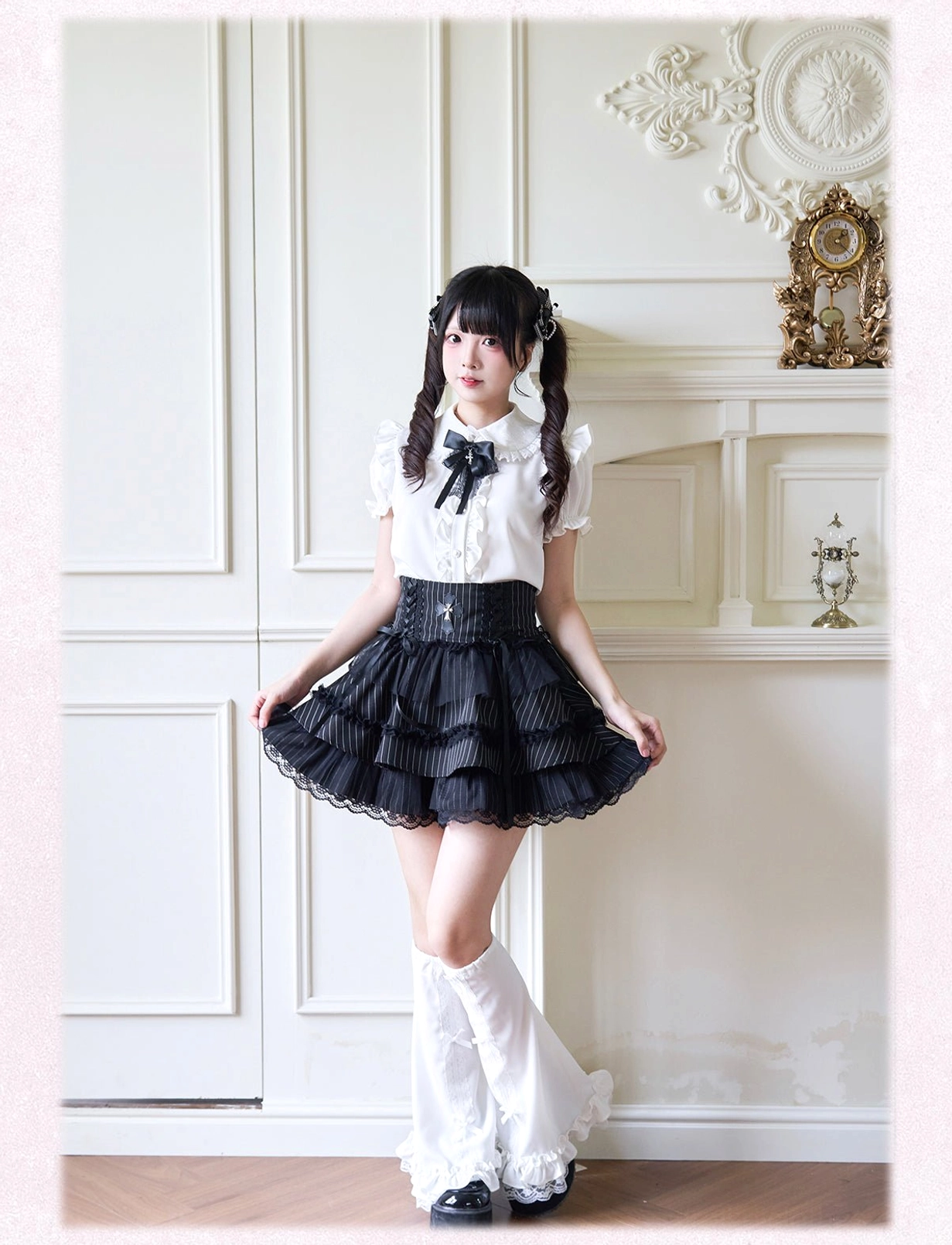 Short-sleeve white Jirai Kei blouse with peter pan collar and frill details styled with white leg warmers front view on paneled wall