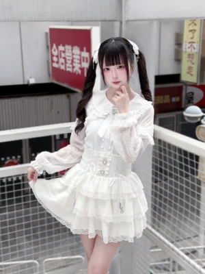 White Jirai Kei lace blouse and tiered ruffle skirt set front three-quarter view on model with twin tails