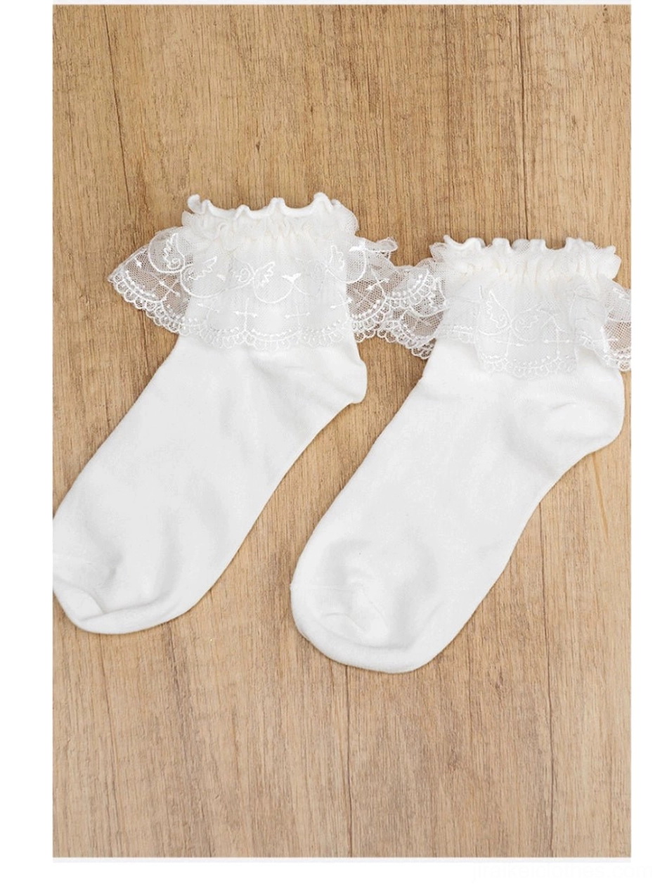 Pair of white Jirai Kei lace ruffle ankle socks flat lay top-down on wood table background matching embroidered cuffs