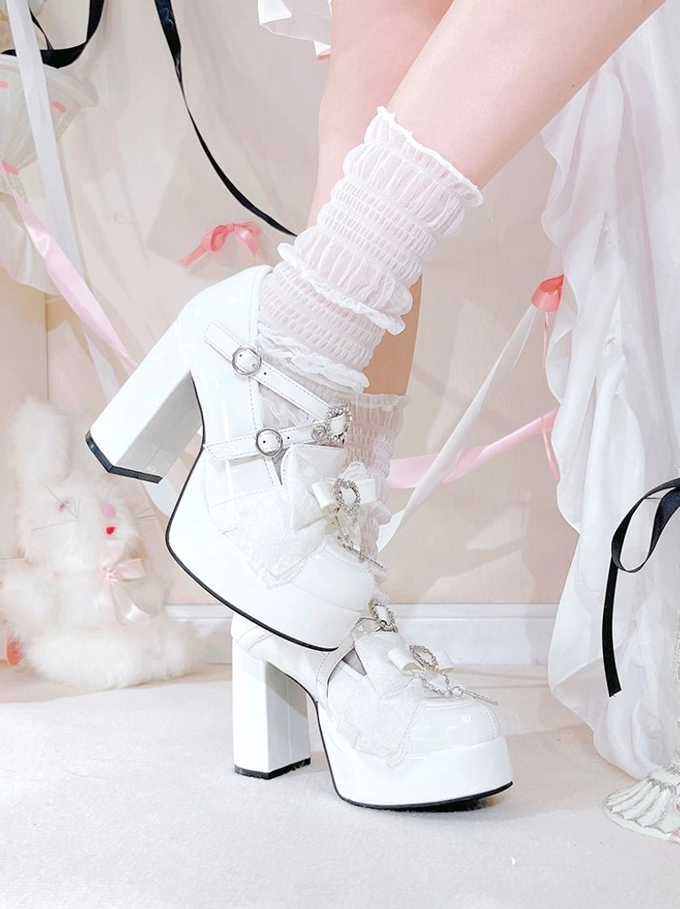 Low-angle side view of white patent Jirai Kei lolita platform shoes with heart-shaped rhinestone accent, platform sole, and delicate feminine bow detail on vamp