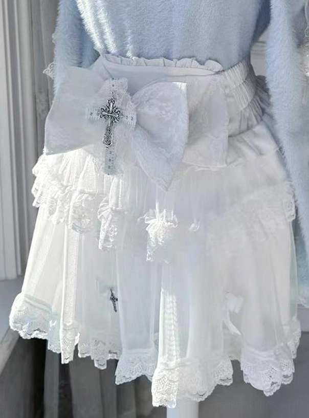 White ruffled Jirai Kei mini skirt with sheer tulle layers, lace hem, and large white cross bow decoration on mannequin