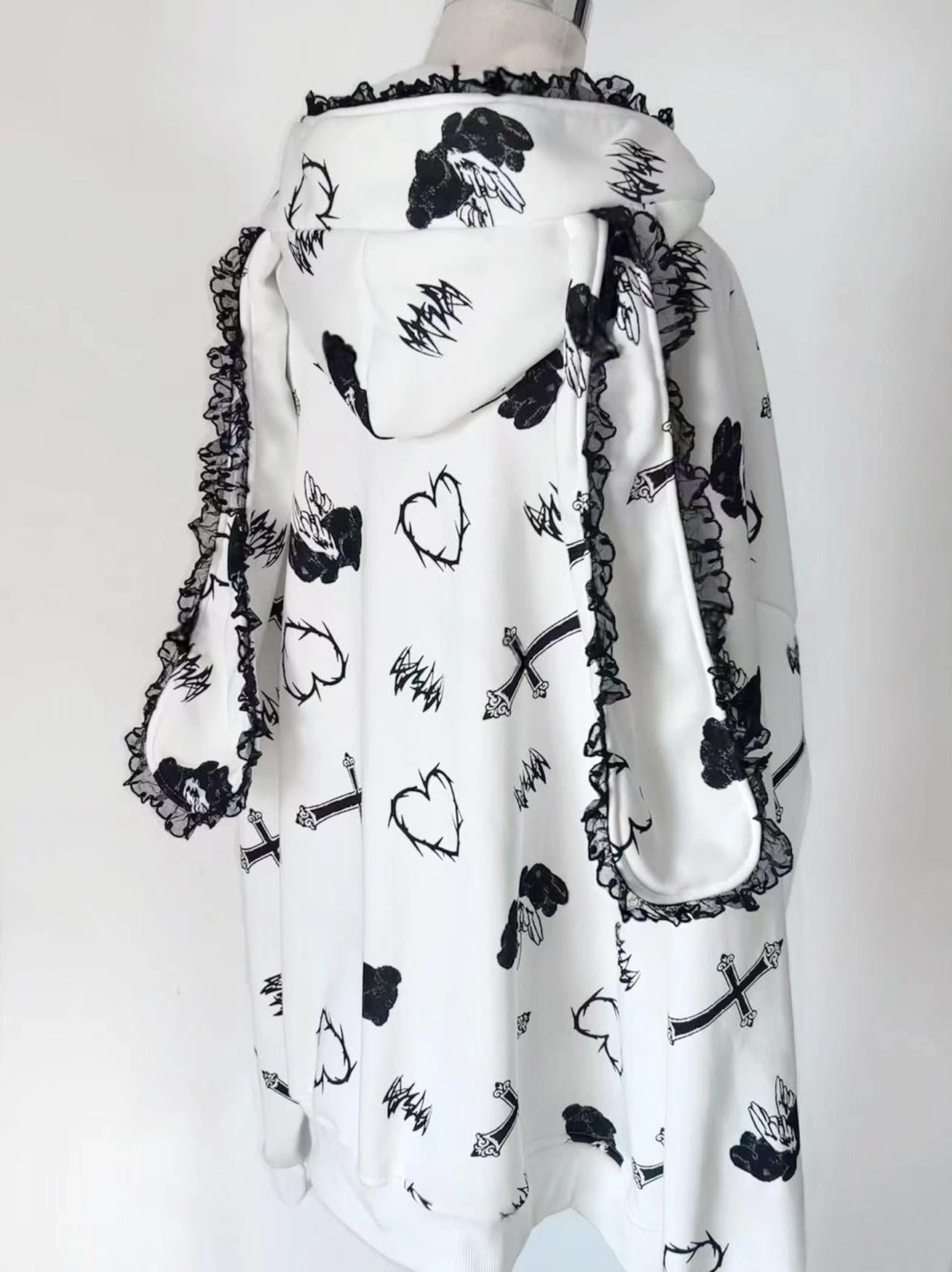 White oversized Jirai Kei hoodie coat three-quarter side product view on studio white background, highlighting black lace trim and heart and cross prints