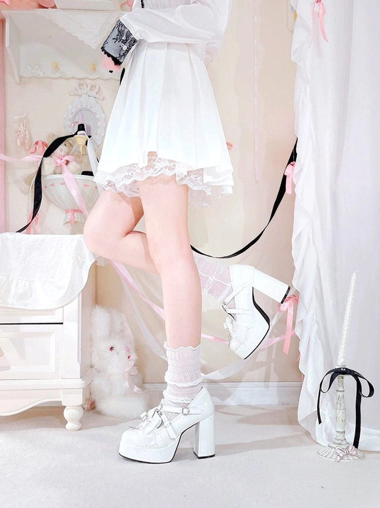 Side profile of white Jirai Kei platform high-heel shoes displaying thick block heel, heart rhinestone decorations, and lace-trimmed vamp bow styling