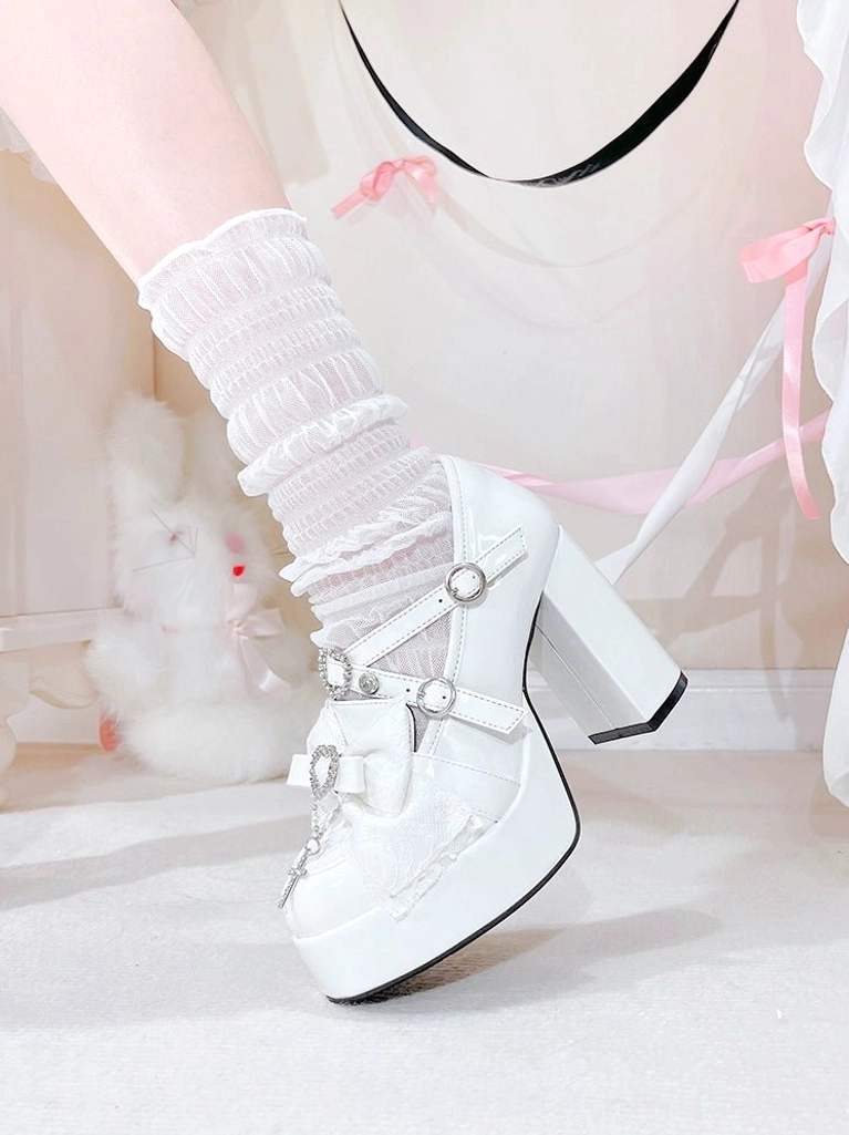 Paired frontal view of white Jirai Kei platform heels with prominent heart-shaped rhinestone decorations, thick platform sole, and glossy patent leather upper