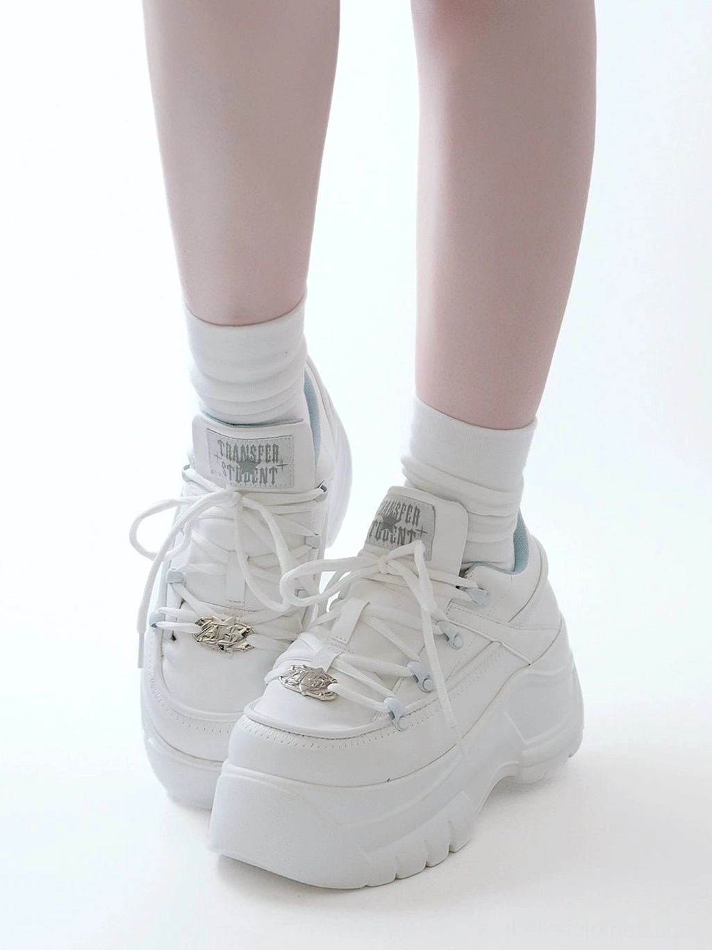 White matte jirai kei platform casual sneakers front three quarter view with white socks displaying chunky outsole and branded tongue tag