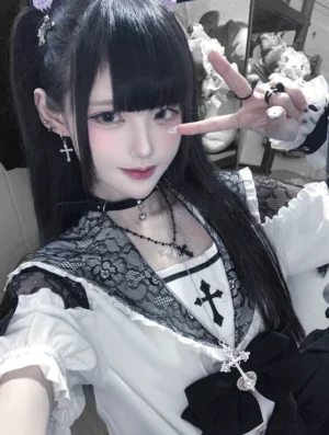 White Jirai Kei sailor collar blouse with cross embroidery and lace sailor collar worn by goth model with twin ponytails close-up front view