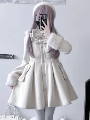 White Lolita style wool fleece winter coat featuring large front bow and furry cuffs on model in casual indoor setting