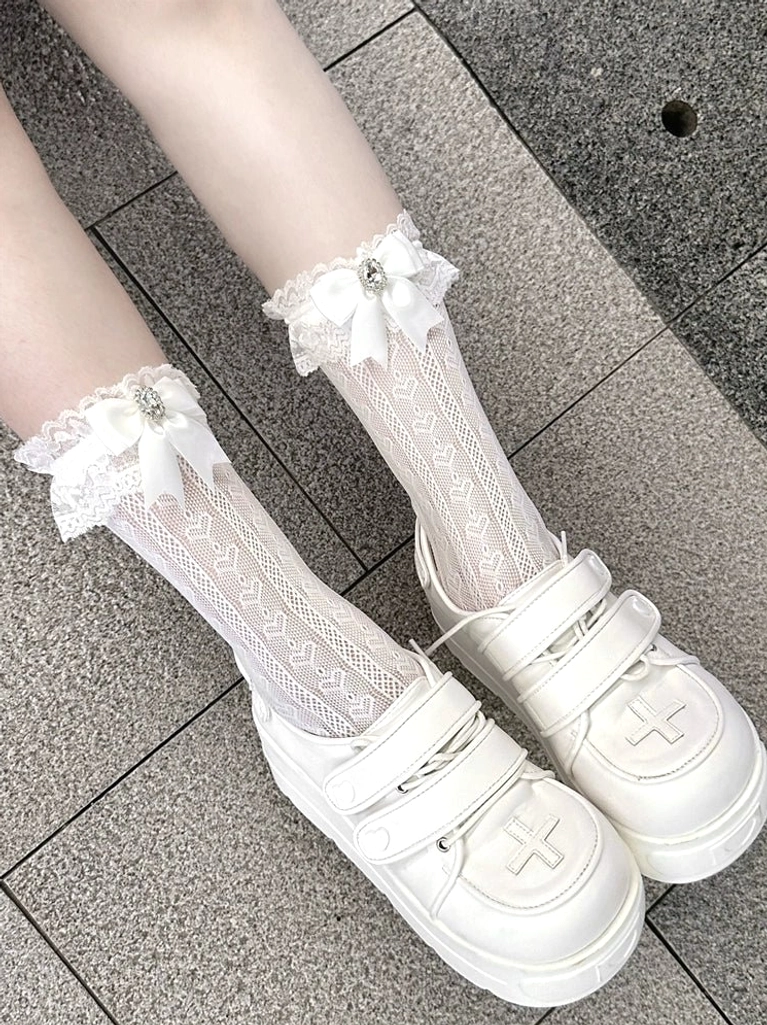 Premium white lace socks with bow and gem accents featuring heart-shaped lace pattern, matching platform shoes with cross embossed detail, top-down close-up view