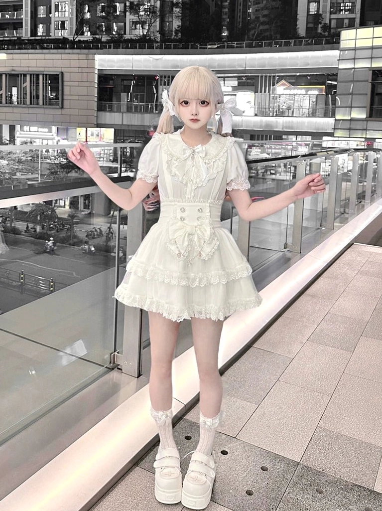 White sweet lolita outfit complete set front view with model in open-arm pose displaying layered ruffle skirt, Peter Pan collar, puffed sleeves, and delicate lace trim