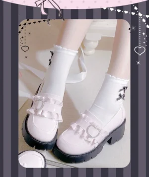 White platform loafers Jirai Kei style with ruffled trim and heart-shaped rhinestone buckle decoration on striped heart-framed background close-up shot