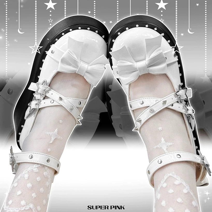 White platform Mary Jane shoes flat lay on starry studio backdrop, paired together showing toe bow, studded straps, and star hardware details on white patent leather