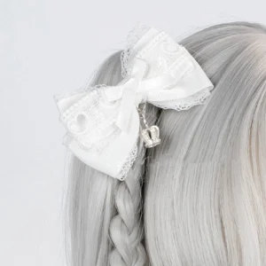 White satin Ryousangata bow hair clip with heart lace edging and hanging silver crown pendant, close-up rear view attached to grey braided synthetic wig showing detailed lace work