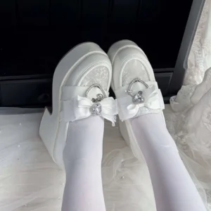 White Ryousangata platform loafers worn with white sheer tights, first-person on-foot view showing satin bow with heart rhinestone buckle