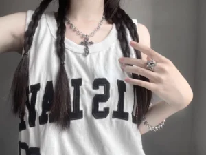 Y2K gothic cross necklace choker styled with sleeveless tee and twin braids, slim silver chain with small cross pendant upper body close-up